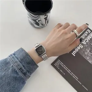 Gros plan d'une montre minimaliste en acier argenté à cadran noir carré sur un poignet