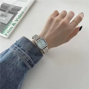 Gros plan d'une montre carrée minimaliste en acier argenté au poignet
