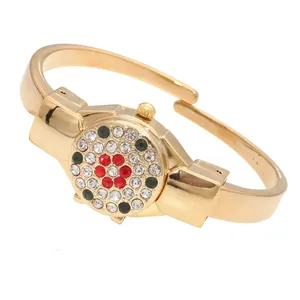 Detail view of a luxury golden bangle watch decorated with colorful rhinestones.