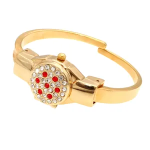 Detail showing a gold ladies bracelet watch with a red and white rhinestone flip-top cover