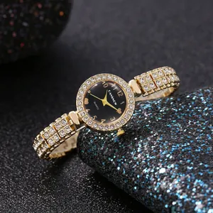 Primo piano di un orologio da donna di lusso in oro con strass su sfondo scuro luccicante