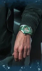 Close-up detail of Mark Fairwhale green skeleton mechanical diving watch worn on male wrist