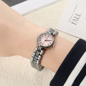 Close-up detail of a vintage silver quartz watch with a soft pink dial on a female wrist