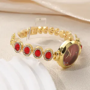 Detail view of luxury gold bracelet watch with red crystal and diamond accents.
