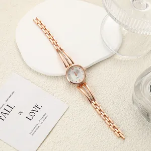 Detail view of a rose gold ladies' watch with rhinestone-studded lugs and steel band