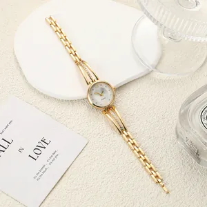 Detailed view of an elegant women's gold quartz watch with rhinestone accents on white stone