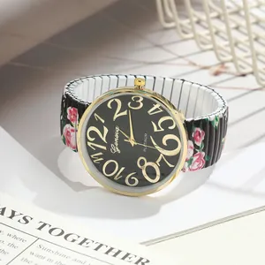 Close-up of ladies' rose print quartz watch with large golden numbers and elastic band.