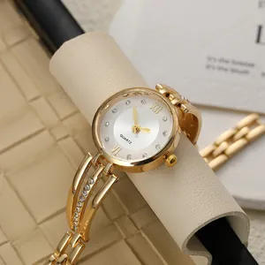 Detailed close-up of a gold-toned women's fashion watch with rhinestone markers and band.