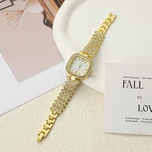 Detailed view of a gold square quartz watch encrusted with shimmering rhinestones.
