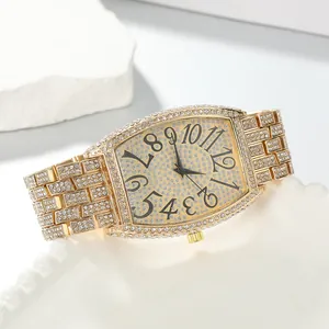 Close-up of luxury gold tonneau watch with full diamond rhinestones and large numerals.