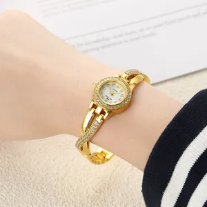 Close-up of women's gold quartz watch with rhinestone crossover bracelet band