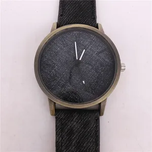 Detailed macro view of bronze quartz watch featuring a black denim textured dial