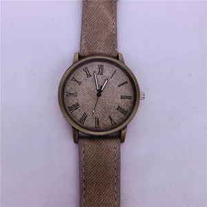 Macro view of a vintage bronze quartz watch featuring a unique denim-textured dial and strap.