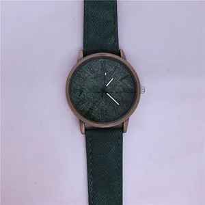 Close-up of green denim texture dial and bronze case of a stylish quartz watch