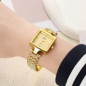 Detail shot of elegant women's square gold watch with full rhinestone chain bracelet
