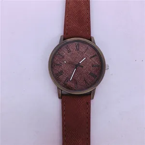 Macro detail of a vintage bronze quartz watch with brown denim texture strap