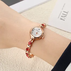 Detail of rose gold bracelet watch for women with red crystals on the model's wrist.