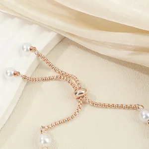 Close-up detail of gold-tone adjustable pearl bracelet featuring pull-type sliding clasp