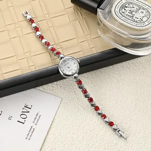 Macro shot of a silver heart-shaped bracelet watch with red crystals on a luxury setting
