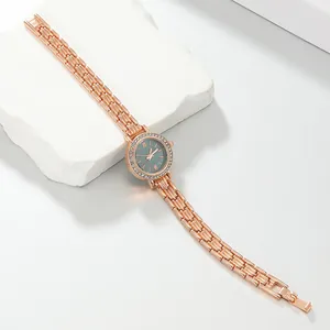 Elegant rose gold ladies bracelet watch with rhinestone bezel displayed on white stone