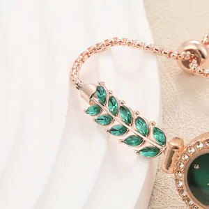 Macro view of a rose gold bracelet watch featuring elegant emerald green leaf crystals