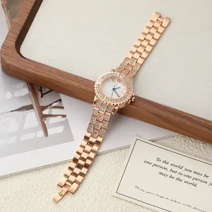 Elegant rose gold women's quartz watch with rhinestone bezel and strap on a wooden tray