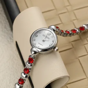 Close-up of elegant lady bracelet watch with red rhinestones and silver steel band