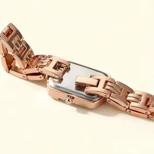 Close-up detail of a rose gold square women's quartz watch with elegant H-link metal band