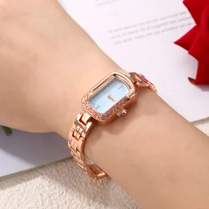 Elegant rose gold rectangular watch with light blue dial and metal link bracelet on wrist