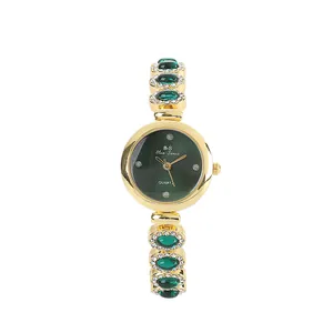 Elegant women's gold-toned jewelry watch with green stones and rhinestone accents.