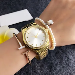 Detail view of gold rhinestone watch paired with pearl clover bracelet on wrist