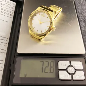 Close-up of elegant gold watch with crystal bezel weighing 72.8g on a digital scale