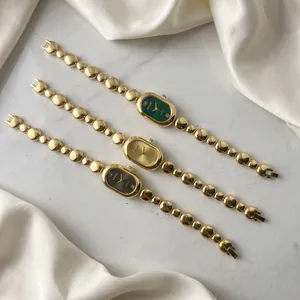 Close-up detail of vintage gold bean chain watches with green, gold and black oval dials.
