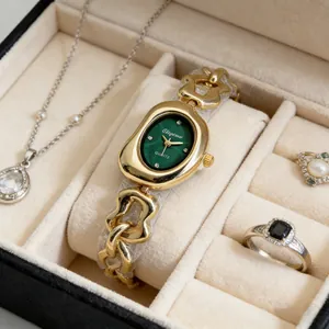 Gros plan d'une montre à quartz dorée pour femme avec cadran ovale vert dans un écrin