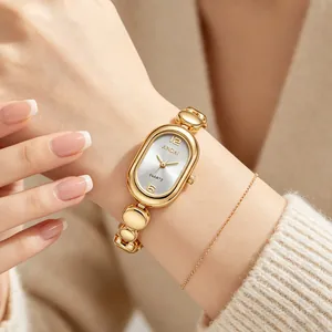 Detailed view of an elegant gold bean link oval women's quartz watch on a model's wrist