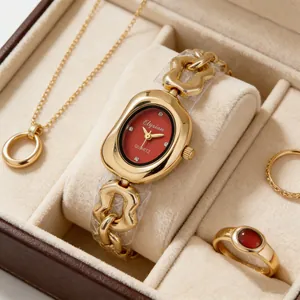 Élégante montre à chaîne dorée avec cadran ovale rouge dans un coffret à bijoux.