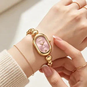 Close-up of elegant gold bean chain watch with oval pink dial on wrist