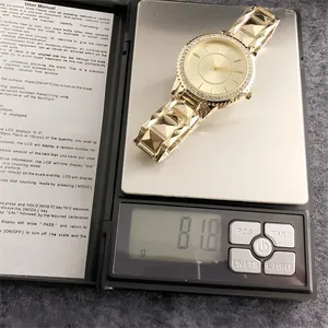 Gold-tone vintage women's watch with rhinestone bezel weighing 81.8 grams on a scale