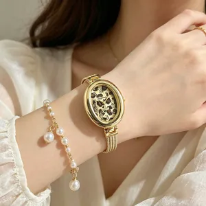 Elegante ovale goldene Uhr mit Leopardenmuster kombiniert mit Perlenarmband-Detail