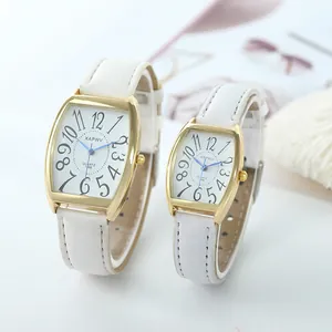 Close-up of elegant gold tonneau couple watches with white leather straps