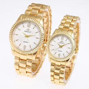 Gros plan sur des montres à quartz dorées pour couple avec bracelets à maillons en acier