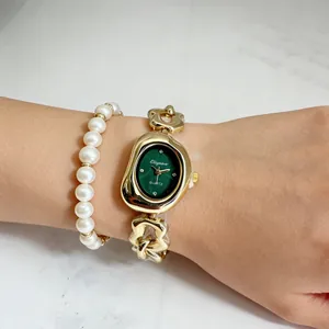 Gros plan détaillé d'une montre à chaîne dorée avec cadran ovale vert et perles