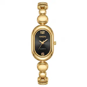 Close-up of elegant gold oval watch with bean link bracelet and black dial