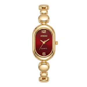 Close-up of elegant oval ladies quartz watch featuring a gold bean chain and deep red dial