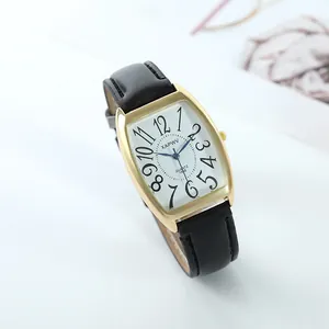 Detailed close-up of a stylish tonneau-shaped gold watch with a premium black leather strap