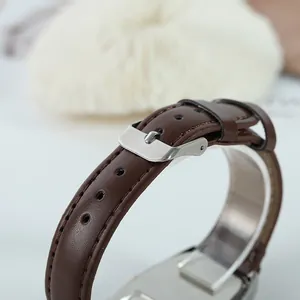 Close-up of brown leather watch strap with classic silver pin buckle detail.