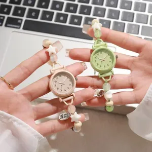 Close-up of cute beaded bracelet watches in green and pink pastel colors.