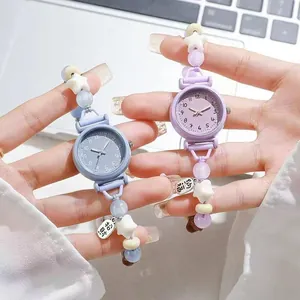 Detail showing two colorful dopamine-style beaded bracelet watches held in hands.
