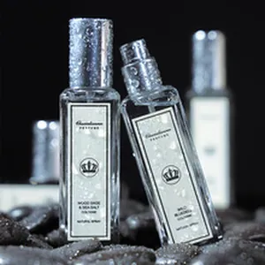 Primo piano di due flaconi di profumo trasparenti con gocce d'acqua su sfondo scuro.