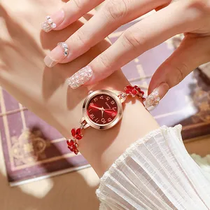 Luxury women's rose gold bracelet watch with red leaf crystal accents and red dial